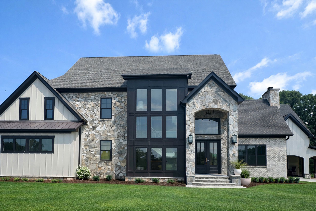 exterior of modern cottage in Shelby, NC, featuring rock, brick, and board and batten siding. Gray, tan, and cream with black accents.
