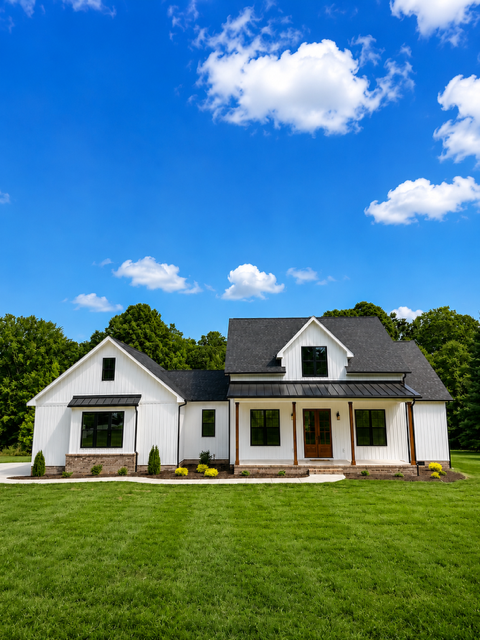 Custom modern farmhouse in Gaffney, South Carolina featuring white board-and-batten siding, black windows, a covered porch, and warm wood accents.